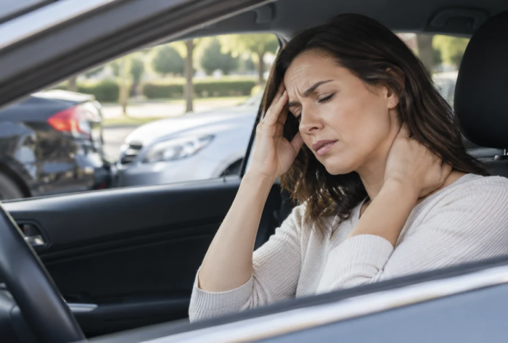 Woman holding her head and neck while experiencing a headache after a car accident