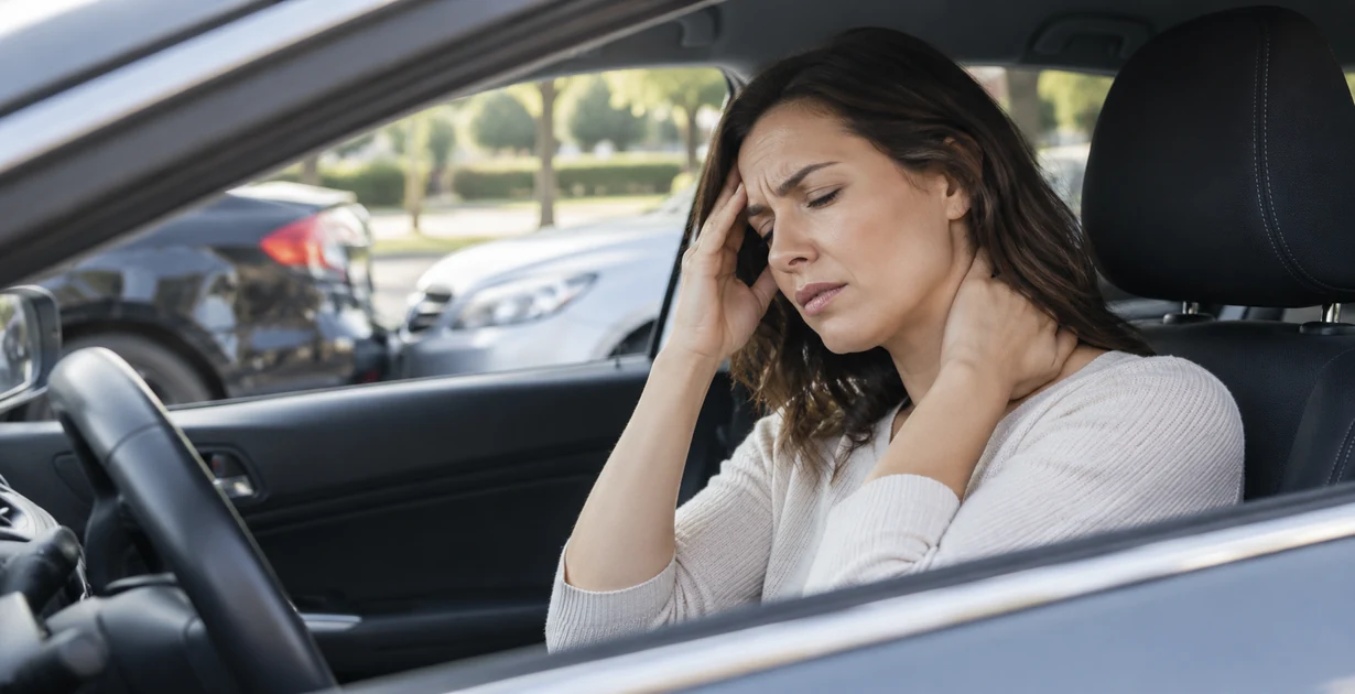 Woman holding her head and neck while experiencing a headache after a car accident